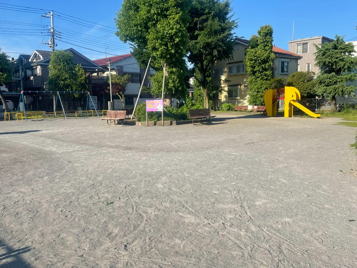 元蕨第一公園の全景。広い砂地の広場にブランコとゾウ型滑り台が並ぶ